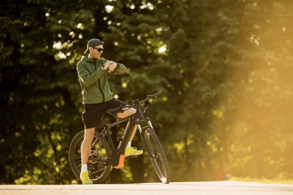 young man with ebike mountain bike with electric battery checking time park Large