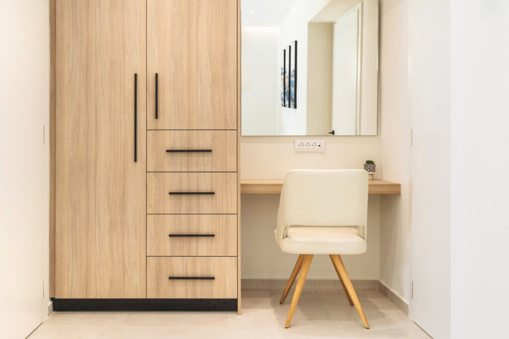A bedroom's work area with a built-in wooden desk and a matching wardrobe, showing a functional and organized space.
