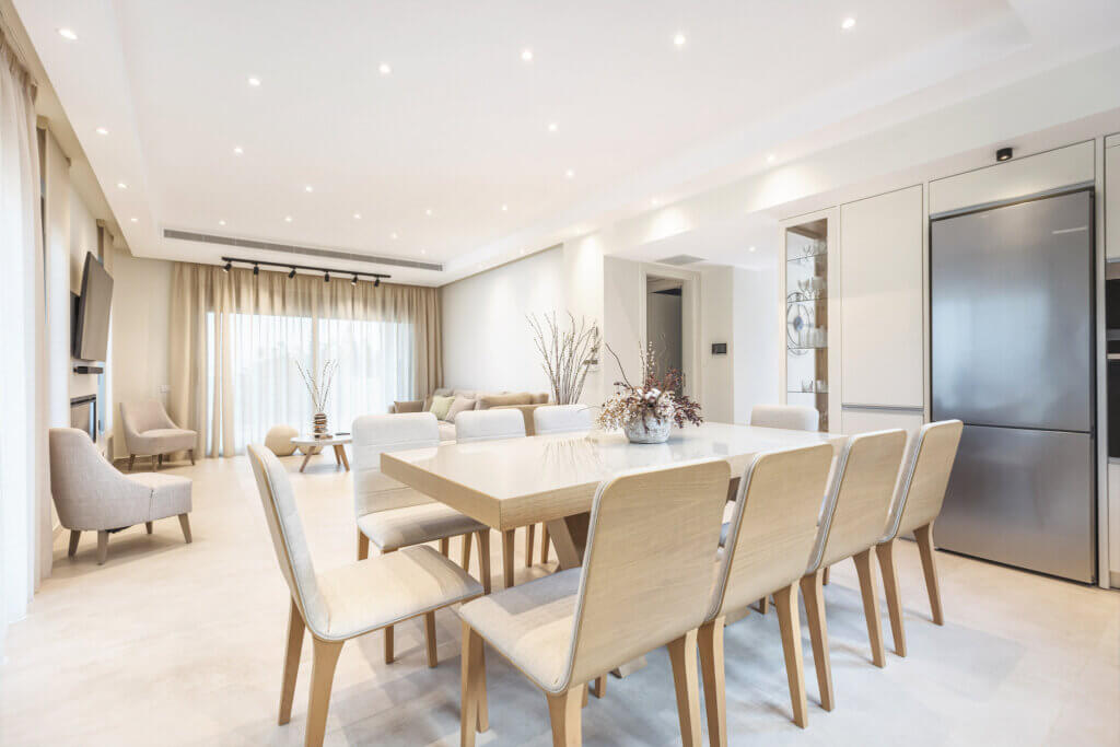 Bright and airy open-concept living space with a large dining table, comfortable seating, and modern kitchen appliances, perfect for social dining and relaxation.